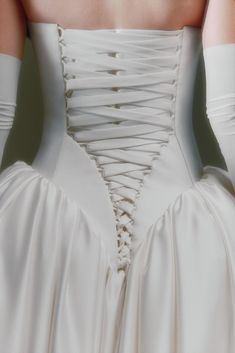 the back of a woman's wedding dress, with white gloves on her arm