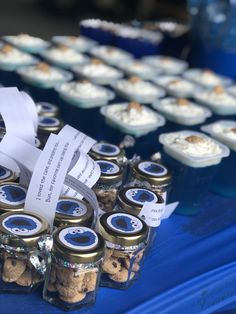 there are many small jars with food in them on the blue tablecloth and white ribbon