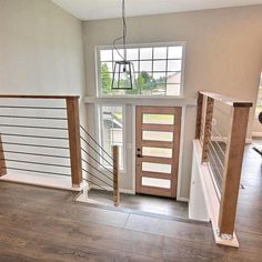 an empty room with wooden stairs and white railings in the center, along with a window on the far wall