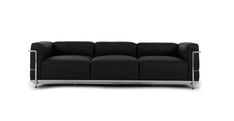 a black couch sitting on top of a white floor next to a metal leg rest