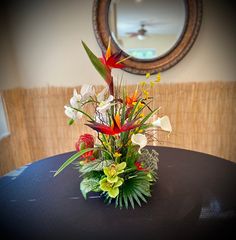 a vase filled with flowers sitting on top of a black table next to a mirror