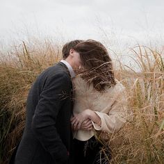 a man and woman kissing in tall grass