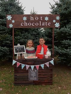 two children standing in front of a hot chocolate stand