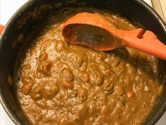 a wooden spoon in a pot filled with beans