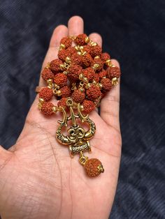 This bold and beautiful Shiva Trident pendant comes on an rudraksh mala gold cap. This is a beautiful way to celebrate your divine masculine energy whatever your gender, and is a beautiful gift for adorning your masculine beloved. See below for more information about this potent, tantric symbol and its meaning. A great gift for yogis and those studying tantra. Brass will oxidize to a more antiqued color over time. If you would like it to be bright and shiny again, just use a little bit of lemon Spiritual Locket Necklace For Navratri, Spiritual Necklaces For Navratri, Brown Necklaces For Puja And Festivals, Festival Brown Necklace For Puja, Gold 108 Beads Mala For Meditation, Spiritual Necklaces For Navratri Gift, Gold Mala With 108 Beads For Meditation, Gold Mala With 8mm Beads For Meditation, Spiritual Necklaces For Meditation And Navratri