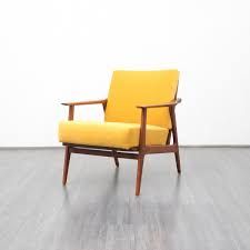 a yellow chair sitting on top of a hard wood floor next to a white wall