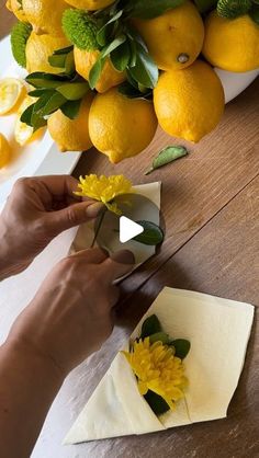 someone is cutting up some paper flowers on a table with lemons in the background