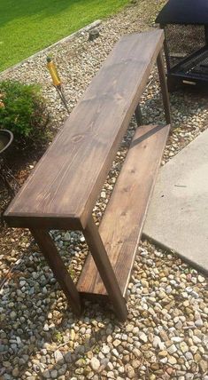 a wooden bench sitting on top of a gravel covered ground