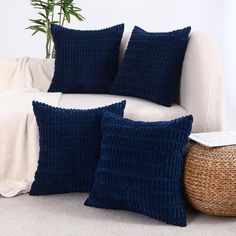 two blue pillows sitting on top of a white couch next to a wicker basket