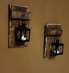 two small lanterns hanging on the side of a wall next to each other, one with a candle in it