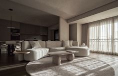 a living room filled with white furniture and windows covered in sheer curtained drapes