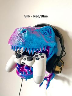 there is a blue and purple dinosaur head with two video game controllers attached to it