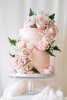 a three tiered cake with pink flowers and baby's breath on the top