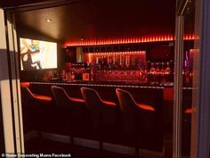 a dimly lit bar with chairs in front of it and a television on the wall