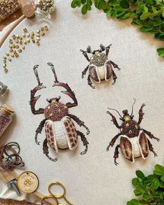 three bugs made out of fabric sitting on top of a table next to scissors and thread