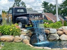 an old truck is parked next to a small pond with water coming out of it