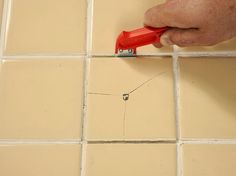 a person is using a red tool to fix a tile floor that has been grouted