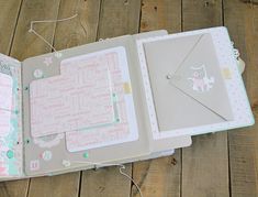 an open planner book with paper and stickers on the pages, sitting on a wooden floor