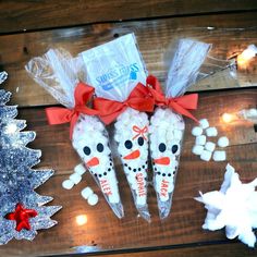 three snowmen made out of marshmallows and candy canes on a wooden table