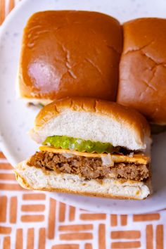 two halves of a sandwich on a white plate next to an orange and white napkin