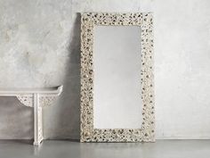 a white mirror sitting next to a bench on top of a cement floor in front of a wall