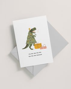 a card with a dinosaur holding a christmas tree