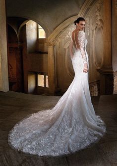 a woman in a white wedding dress posing for the camera with her back to the camera