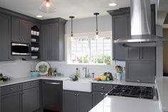 a kitchen with gray cabinets and white counter tops