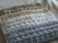 there is a crocheted dish cloth on top of a bed sheet with white and gray stripes