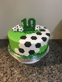 a birthday cake with soccer balls and the number ten on it, sitting on a table