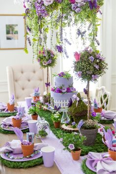 a table topped with lots of purple and green flowers next to potted planters