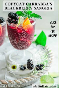 two glasses filled with blackberries and oranges on top of a tray next to lime slices