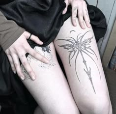 a woman with tattoos on her legs sitting next to another person's leg and arm