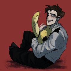 a man sitting on the ground holding a banana