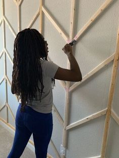 a woman standing in front of a wall holding a paint roller and painting the walls