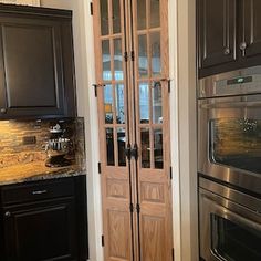 a kitchen with black cabinets and stainless steel stove top oven in the corner next to an open pantry door