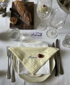 a table set with white linens and silverware