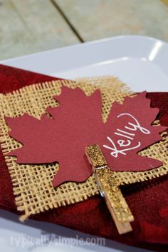 a red and gold place card with a cross on it that says hello fall leaves