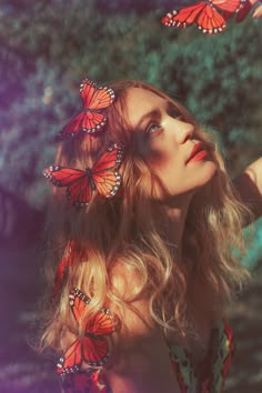 a woman with long blonde hair and red butterflies on her head is looking up at the sky