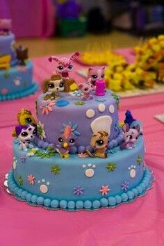 there is a blue cake decorated with littlest pet shop animals on it's sides