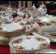 a table topped with lots of white and gold plates covered in floral designs on top of each other