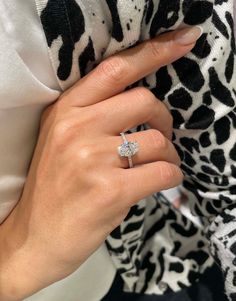 a woman's hand with a diamond ring on her left hand, wearing a leopard print shirt