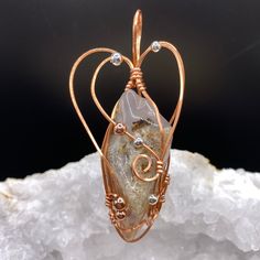 This beautiful dendritic opal has hints of grey/lavender, cream, and a slight peach hue.  It is called 'dendritic' due to the branch-like inclusions visible inside of the stone.  Copper wire was chosen for the wrapping wire to enhance the peach hue of the bottom half of the stone.  Ancient customs and lore indicate that gemstones can bring peace, health, protection and spiritual favor.  Dendritic opal is believed to aid in the discovery of the true self, determining your vision in life, and living with a positive outlook in life in accordance with divine purpose.   The pendant measures 2 3/4 inches high by 1 inch wide by 3/4 inch front to back.  The bale opening measures 1/3 inches high by 1/2 inches wide.    A complimentary faux suede cord with a 2-inch extender chain is included with thi Brown Untreated Jewelry Gift, Untreated Amber Jewelry Gift, Lavender Cream, Divine Purpose, Grey Lavender, Dendritic Opal, Suede Cord, True Self, Black Gift Boxes