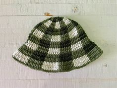 a green and white crocheted hat hanging on the wall