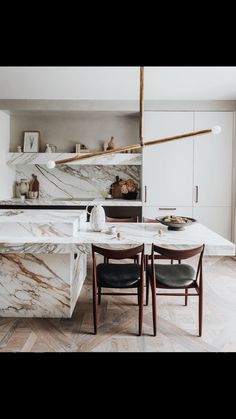 a kitchen with marble counter tops and chairs