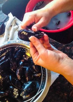 a person holding a spoon over a bowl of mussels