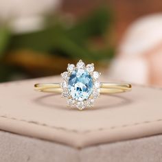 a blue and white ring sitting on top of a box next to a flower arrangement