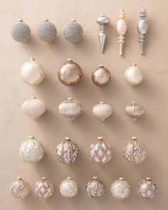 a collection of christmas ornaments arranged on a beige background with white and silver decorations around them