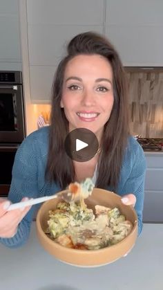 a woman is holding a bowl of food in her hands and smiling at the camera