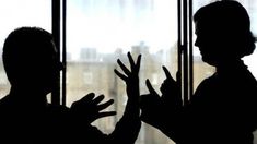 two people standing next to each other in front of a window